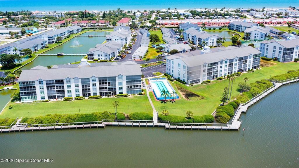 An aerial view shows multi-story apartment buildings, a swimming pool, and a wooden dock — 580 S BREVARD AVENUE UNIT 815, COCOA BEACH, FL
