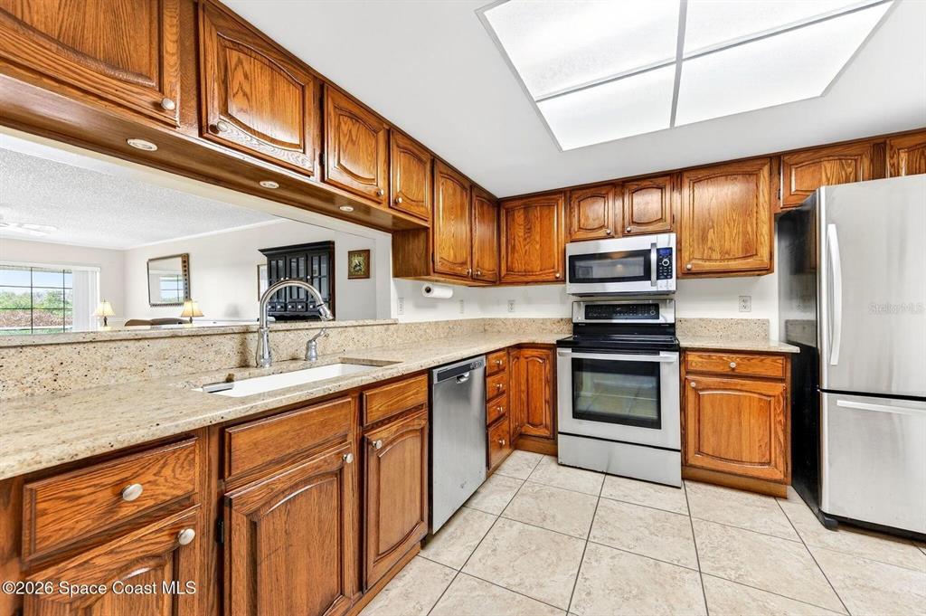 A kitchen features wood cabinets, granite countertops, stainless steel appliances, and tile flooring — 580 S BREVARD AVENUE UNIT 815, COCOA BEACH, FL