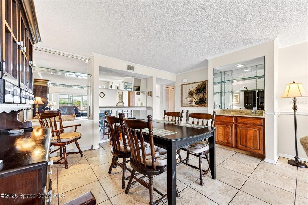 A dining room features a dark wood table, matching chairs, tiled floors, and a wet bar — 580 S BREVARD AVENUE UNIT 815, COCOA BEACH, FL
