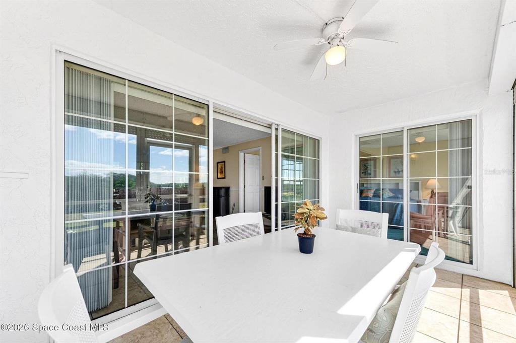 A white dining set sits on a tiled patio overlooking a screened-in porch area — 580 S BREVARD AVENUE UNIT 815, COCOA BEACH, FL