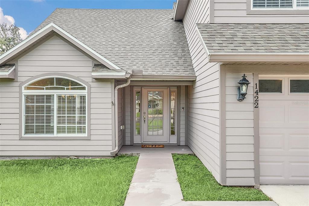 The exterior of a gray house features a front door, a window, and a garage — 1422 SAFFRON TRAIL, DELAND, FL