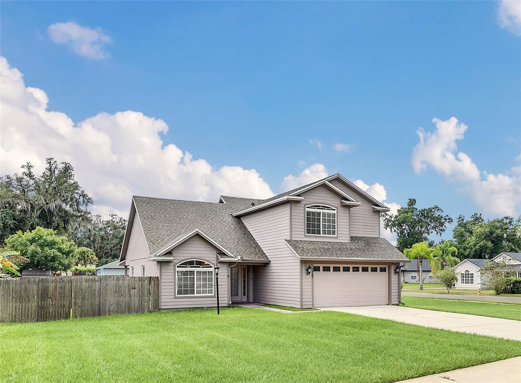 A two-story suburban house with light-colored siding, a two-car garage, and a wooden fence — 1422 SAFFRON TRAIL, DELAND, FL