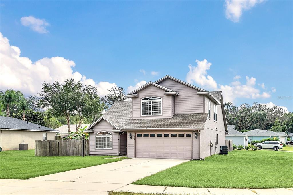 A two-story suburban house with a beige exterior, a two-car garage, and a concrete driveway — 1422 SAFFRON TRAIL, DELAND, FL