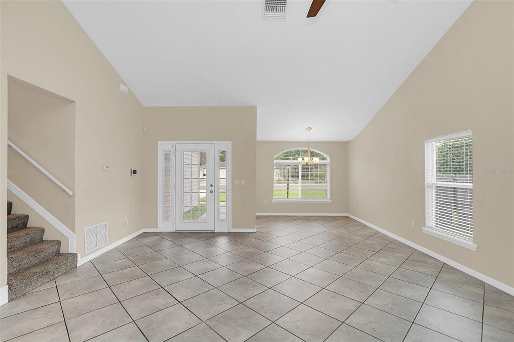 An open-concept living area features vaulted ceilings, tile flooring, a staircase, and a front entrance — 1422 SAFFRON TRAIL, DELAND, FL