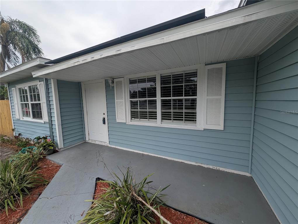 A light blue house exterior features a front porch, white shutters, and a white door — 111 W GRAPEFRUIT CIRCLE, CLEARWATER, FL