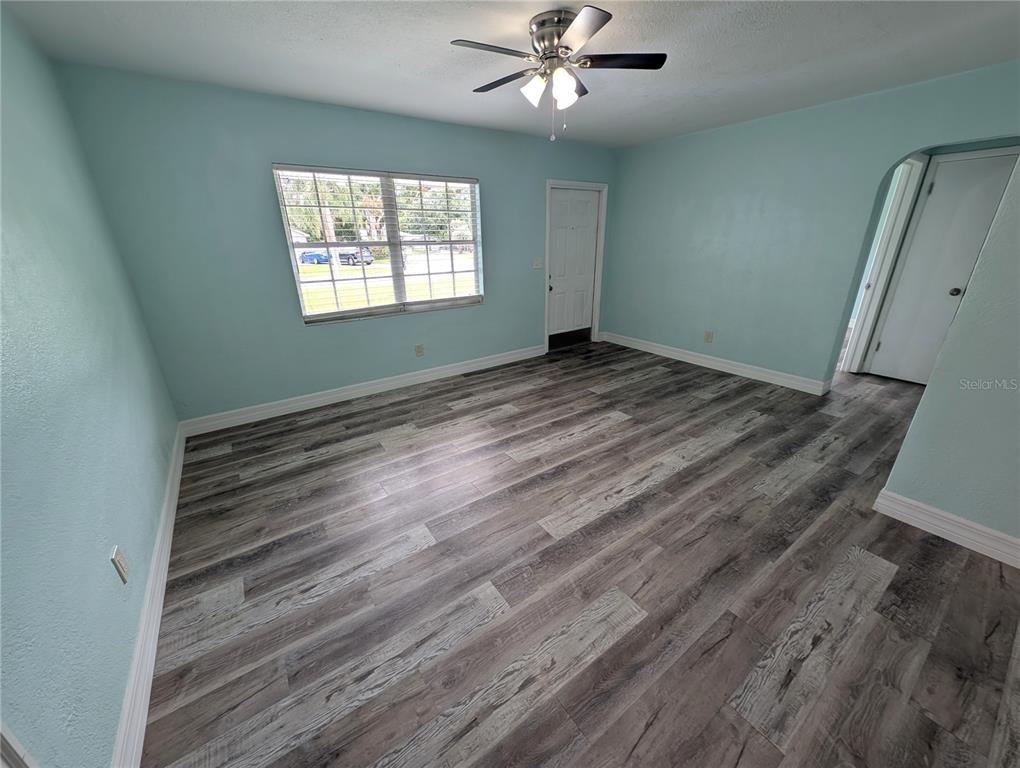 An empty room with light blue walls, wood-look flooring, a ceiling fan, and a window — 111 W GRAPEFRUIT CIRCLE, CLEARWATER, FL
