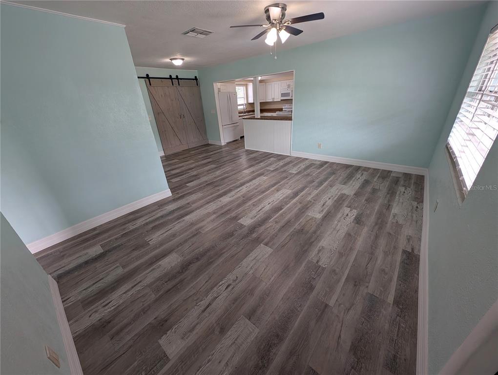 A living room with light blue walls, gray wood-look flooring, and a sliding barn door — 111 W GRAPEFRUIT CIRCLE, CLEARWATER, FL