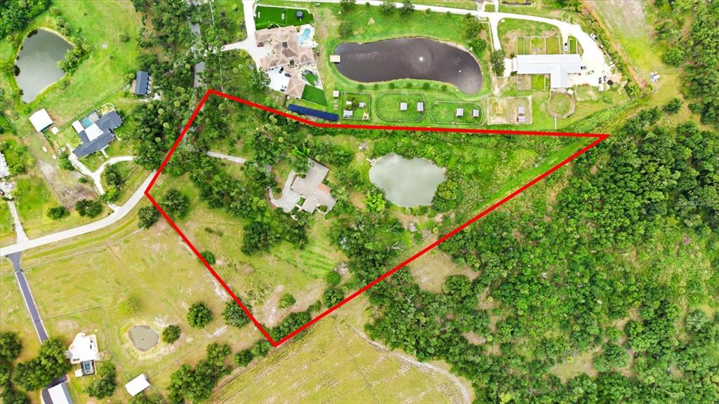 An aerial view shows a house nestled among trees near a pond and open fields — 5850 VANDERIPE ROAD, SARASOTA, FL