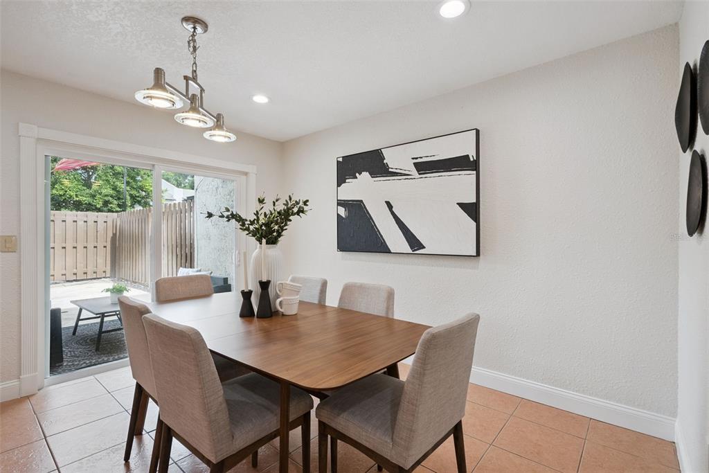 A dining room features a wooden table, six chairs, modern lighting, and a sliding glass door — 1713 GULFVIEW DRIVE UNIT 435B, MAITLAND, FL