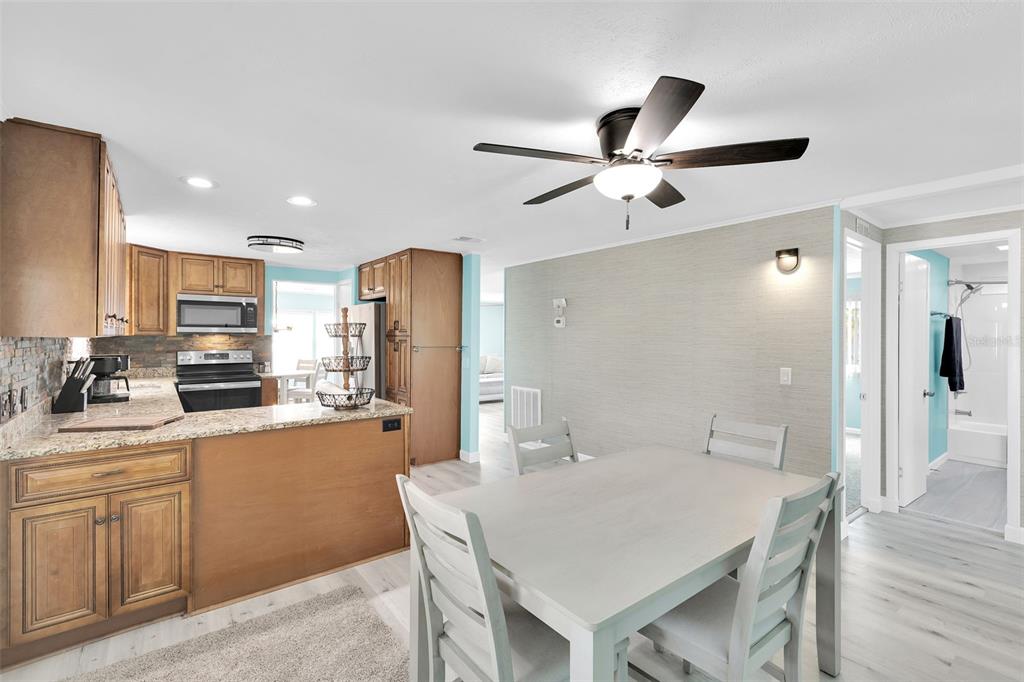 A dining area with a light-colored table sits adjacent to a kitchen with wood cabinets — 517 LOS ALTOS, NORTH PORT, FL