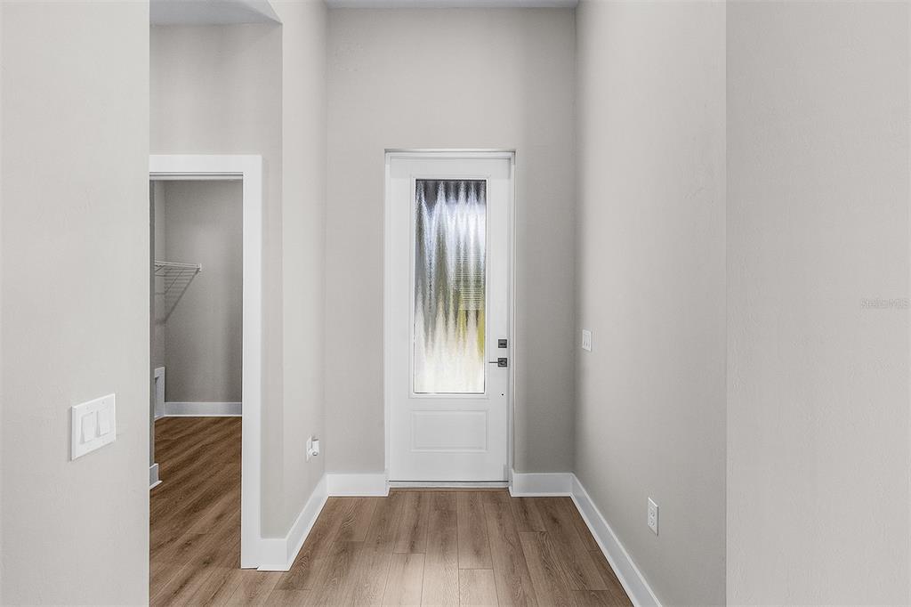 An entryway with light wood-look flooring, white walls, and a door with a frosted glass insert — 5321 CRESTLINE TERRACE, PORT CHARLOTTE, FL