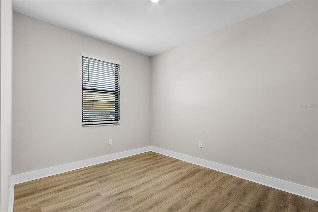 An empty room with light gray walls, wood-look flooring, and a single window with blinds — 5321 CRESTLINE TERRACE, PORT CHARLOTTE, FL