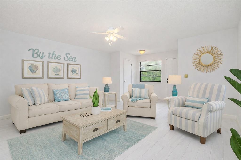 A bright living room features a beige sofa, striped armchair, and light wood coffee table — 4152 66TH STREET CIRCLE W, BRADENTON, FL