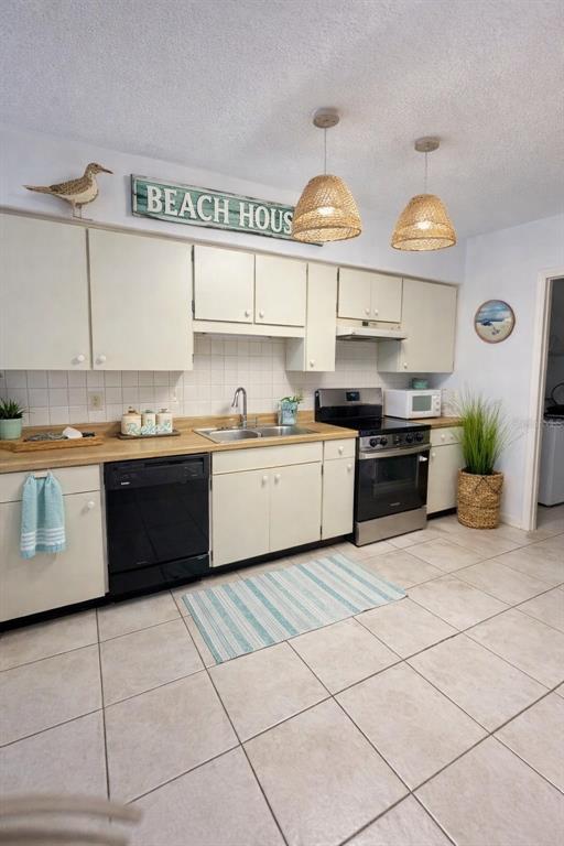 A kitchen features off-white cabinets, a black dishwasher, a stainless steel stove, and tile flooring — 4152 66TH STREET CIRCLE W, BRADENTON, FL