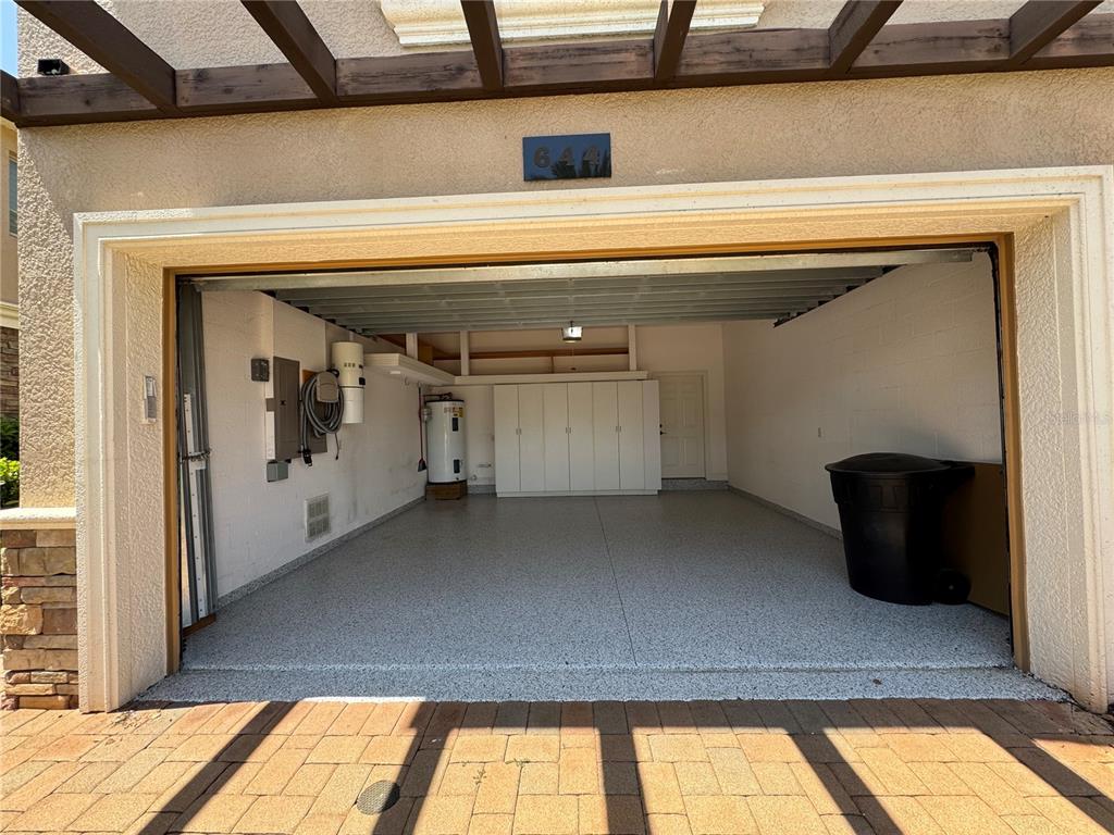 An open garage with a speckled epoxy floor, built-in cabinets, and a water heater — 644 SAXONY BOULEVARD, ST PETERSBURG, FL