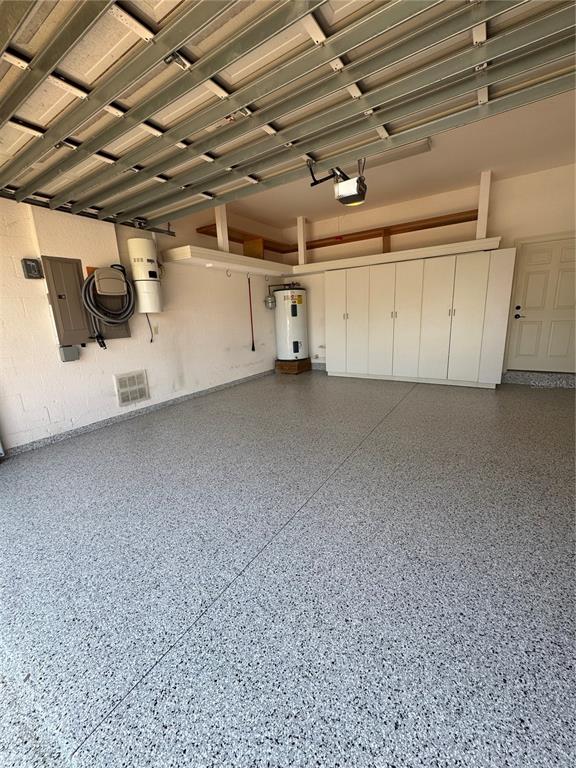 A garage with a speckled epoxy floor, built-in cabinets, and a water heater — 644 SAXONY BOULEVARD, ST PETERSBURG, FL