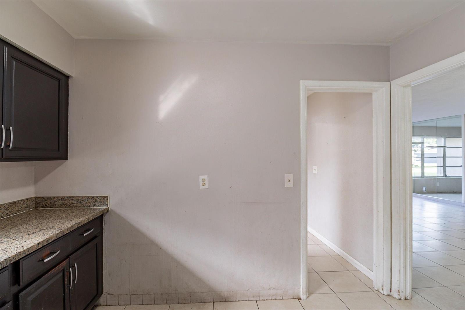A kitchen wall with dark cabinets, granite countertops, and a doorway leading to another room — 404 NW 5th Avenue, Boynton Beach FL 33435, BOYNTON BEACH, FL