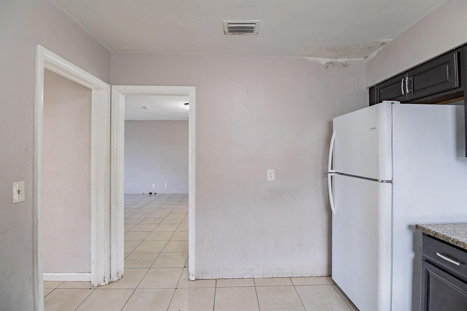 A kitchen area features a white refrigerator, dark cabinets, and a doorway leading to another room — 404 NW 5th Avenue, Boynton Beach FL 33435, BOYNTON BEACH, FL