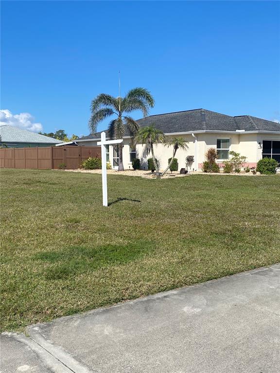 A vacant grassy lot sits in front of a single-story house with palm trees — 4280 OAK TERRACE CIRCLE, PORT CHARLOTTE, FL