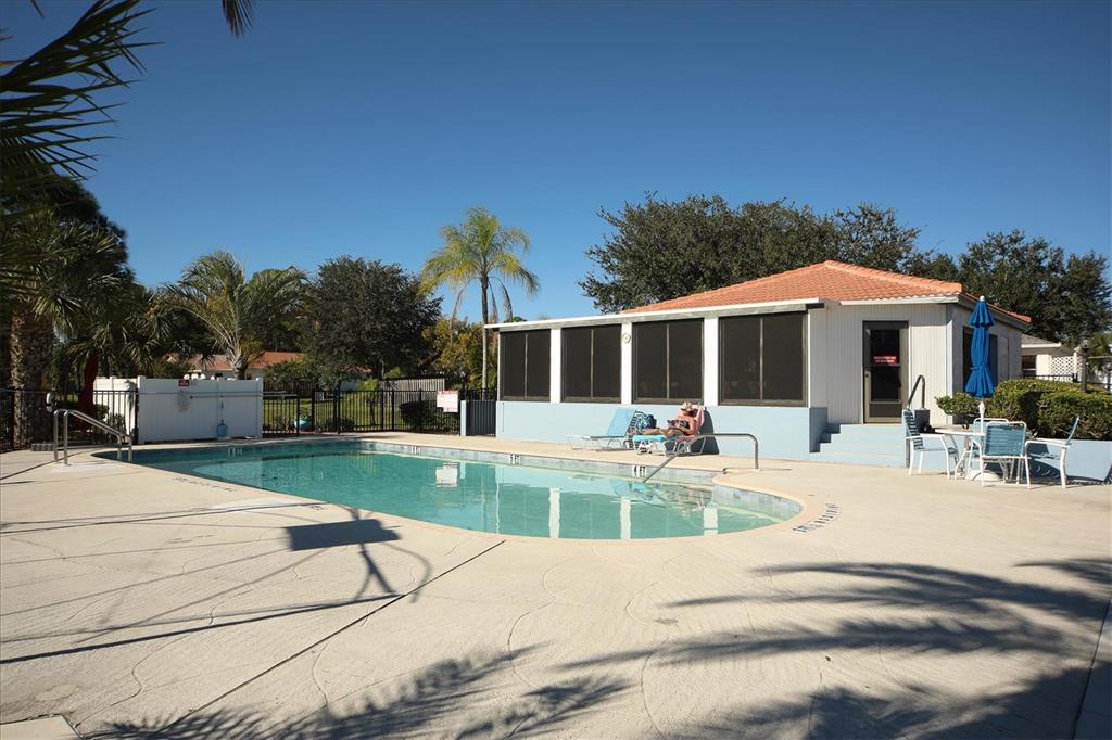 An outdoor swimming pool with a surrounding concrete deck and a small clubhouse building — 4280 OAK TERRACE CIRCLE, PORT CHARLOTTE, FL