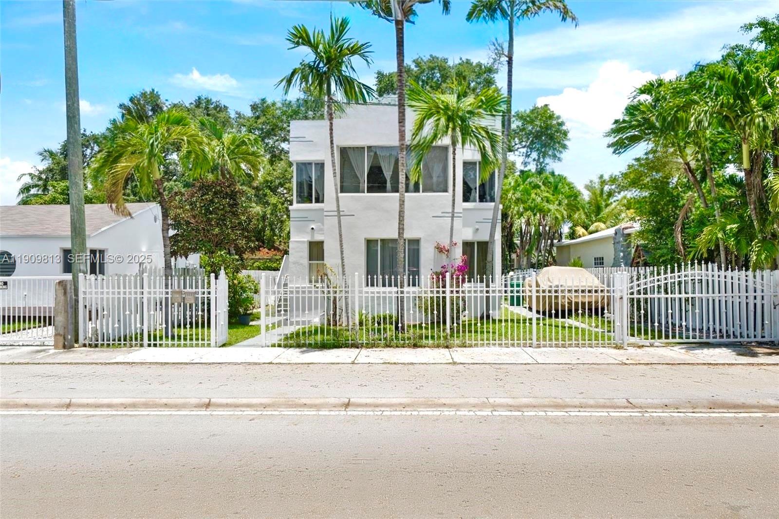 A two-story white house with large windows sits behind a white metal fence — 555 NE 70th St, Miami FL 33138, MIAMI, FL