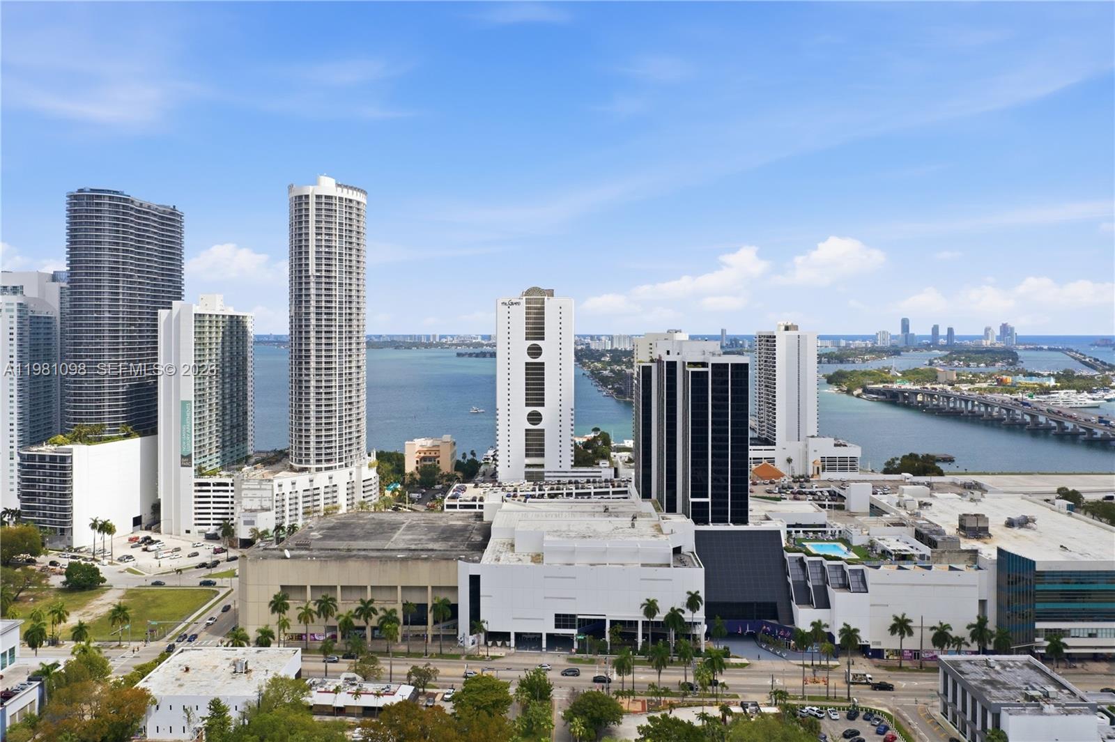 An aerial view shows high-rise buildings and a shopping center near a bay in Miami — 1600 NE 1st Ave # 1610, Miami FL 33132, MIAMI, FL
