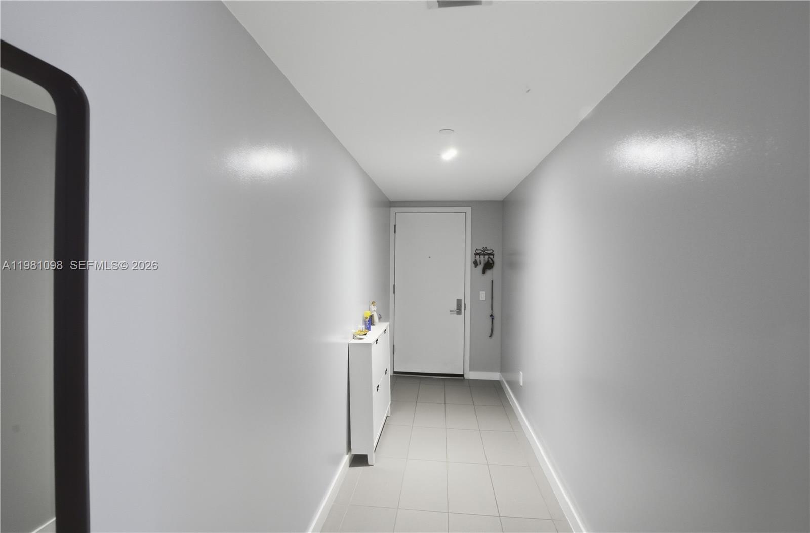 A narrow hallway features gray tile flooring, light gray walls, and a white entry door — 1600 NE 1st Ave # 1610, Miami FL 33132, MIAMI, FL