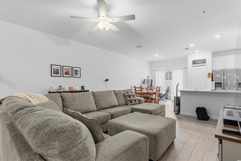 A living room with a large sectional sofa, ceiling fan, and an open kitchen area — 12657 NW 7TH PLACE, NEWBERRY, FL