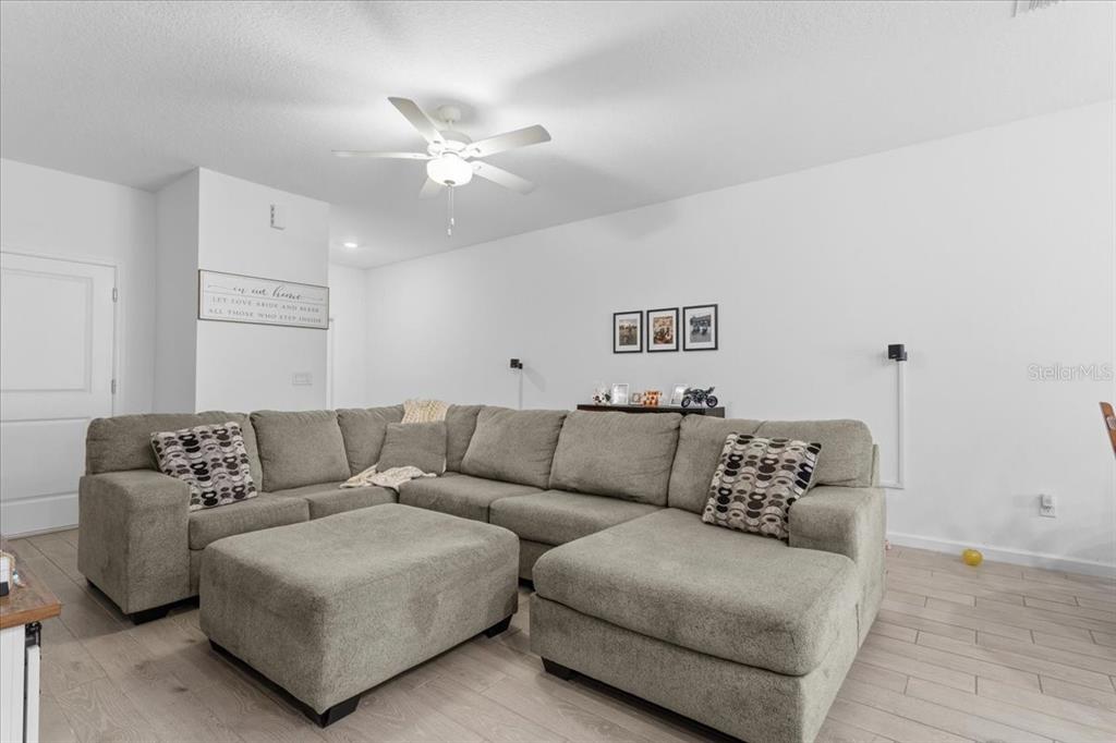 A living room features a large gray sectional sofa with an ottoman and light flooring — 12657 NW 7TH PLACE, NEWBERRY, FL