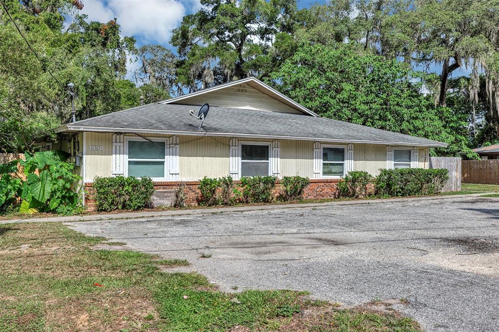 A single-story building with yellow siding, a brick base, and a gray shingled roof — 3990 SE 17TH COURT, OCALA, FL