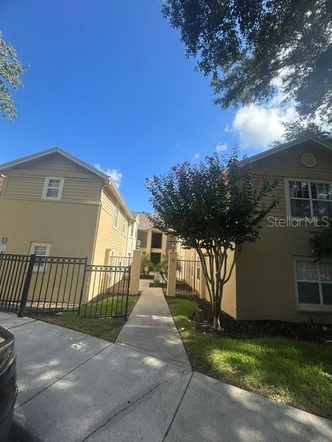 A sidewalk leads between two tan, multi-story apartment buildings with black metal fencing — 425 SUMMIT RIDGE PLACE UNIT 105, LONGWOOD, FL