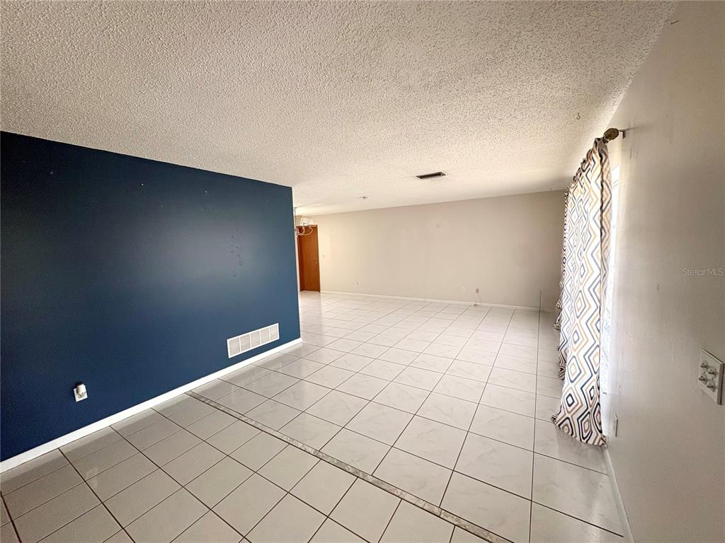 A room with white tiled floors, a dark blue accent wall, and patterned curtains — 13 FLARESTONE COURT, PALM COAST, FL