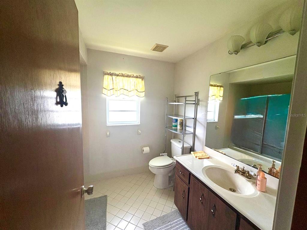 A bathroom features a vanity with a sink, a toilet, and a metal shelving unit — 13 FLARESTONE COURT, PALM COAST, FL