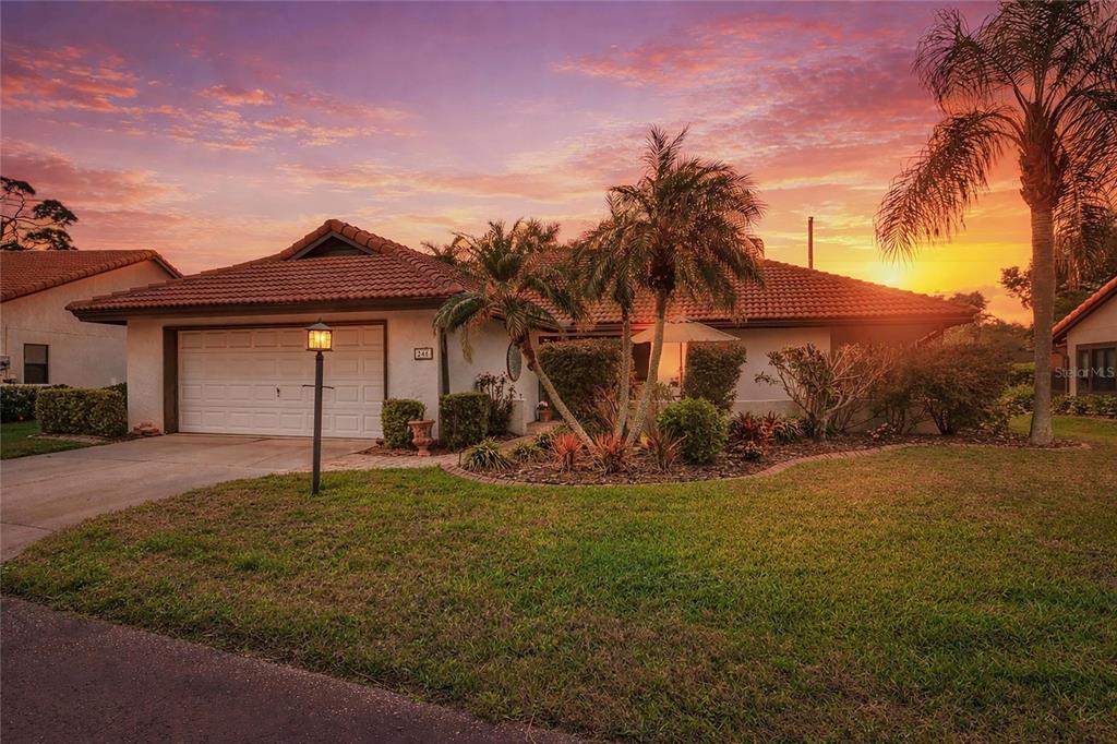 A single-story house with a tiled roof and a two-car garage at sunset — 246 LAUREL HOLLOW DRIVE UNIT 23, NOKOMIS, FL