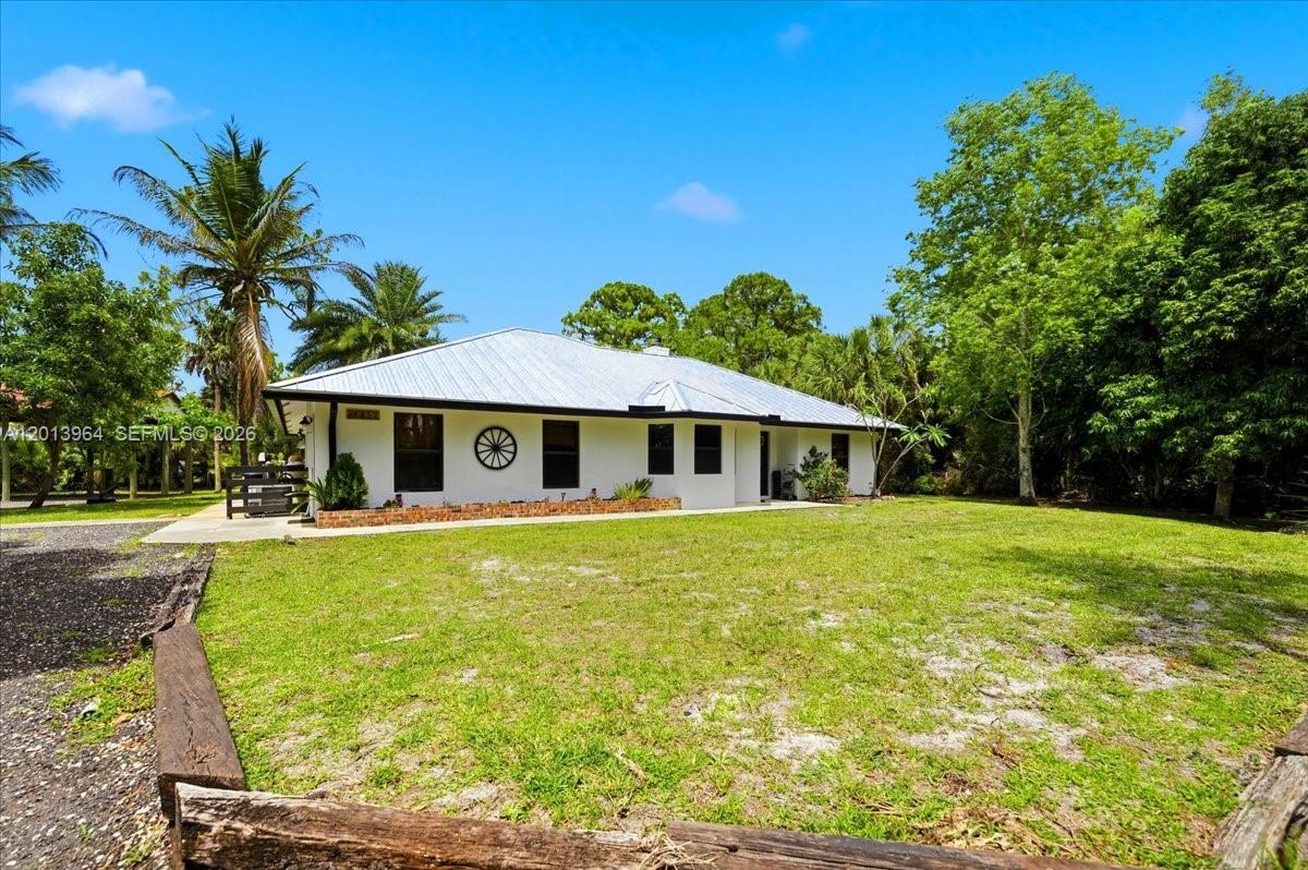 A white single-story house with a metal roof sits on a grassy lot — 17857 82nd Rd N, Loxahatchee FL 33470, LOXAHATCHEE, FL