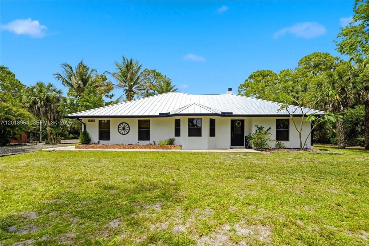 A white single-story house with a metal roof sits on a grassy lot — 17857 82nd Rd N, Loxahatchee FL 33470, LOXAHATCHEE, FL