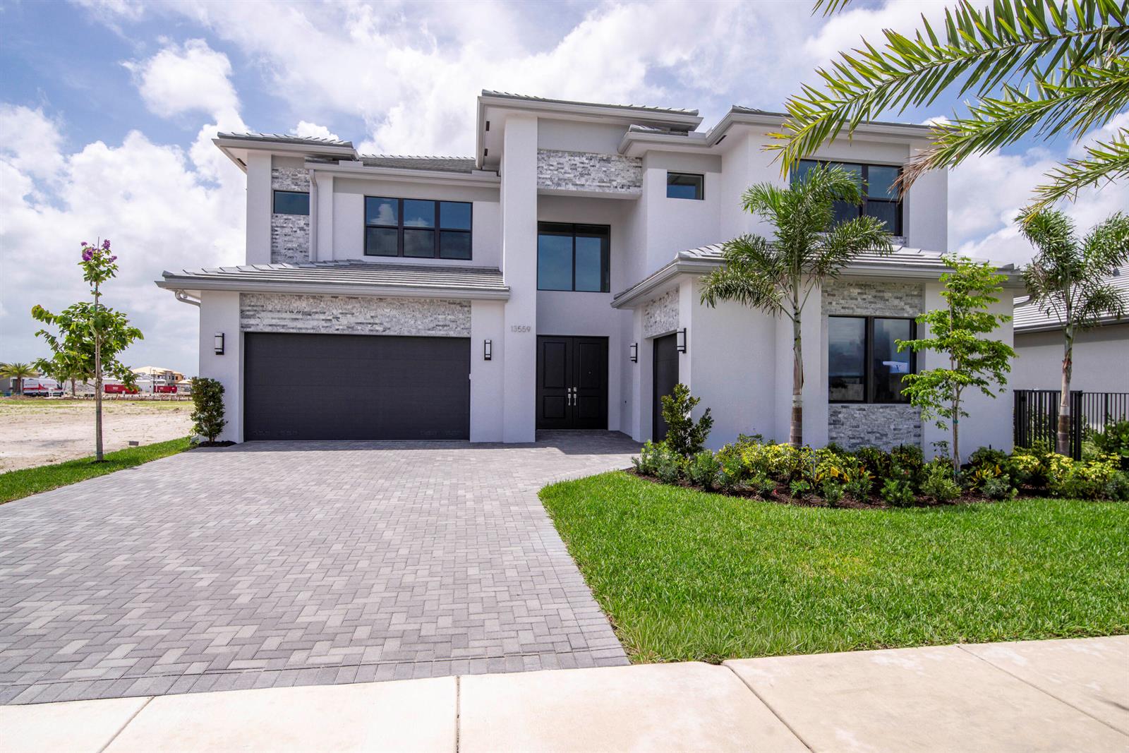 A two-story modern house with a stone-accented facade, a paved driveway, and a front lawn — 13559 Nesting Pines Way, Palm Beach Gardens FL 33412, PALM BEACH GARDENS, FL