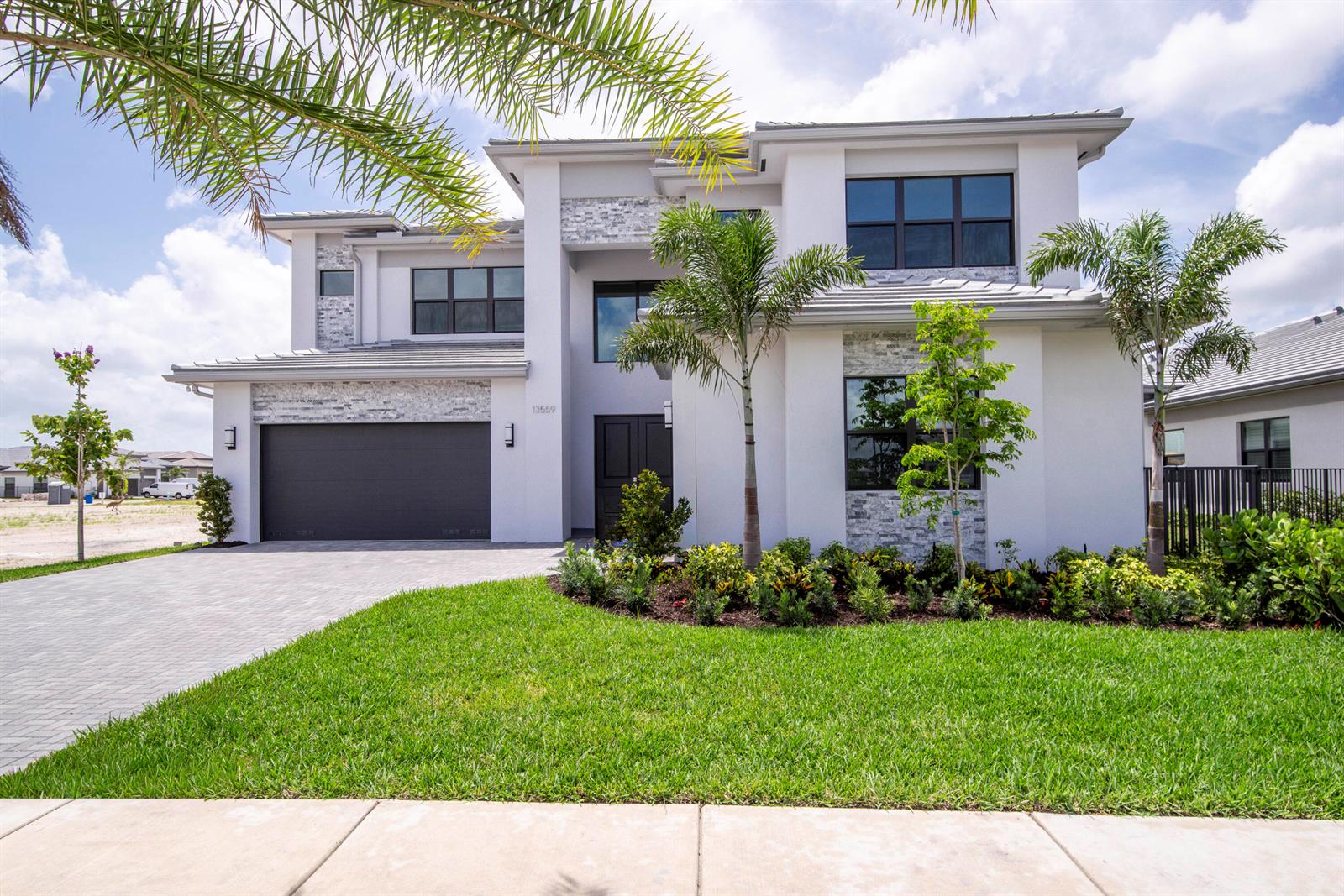 A two-story modern house with a gray garage, stone accents, and palm trees in front — 13559 Nesting Pines Way, Palm Beach Gardens FL 33412, PALM BEACH GARDENS, FL