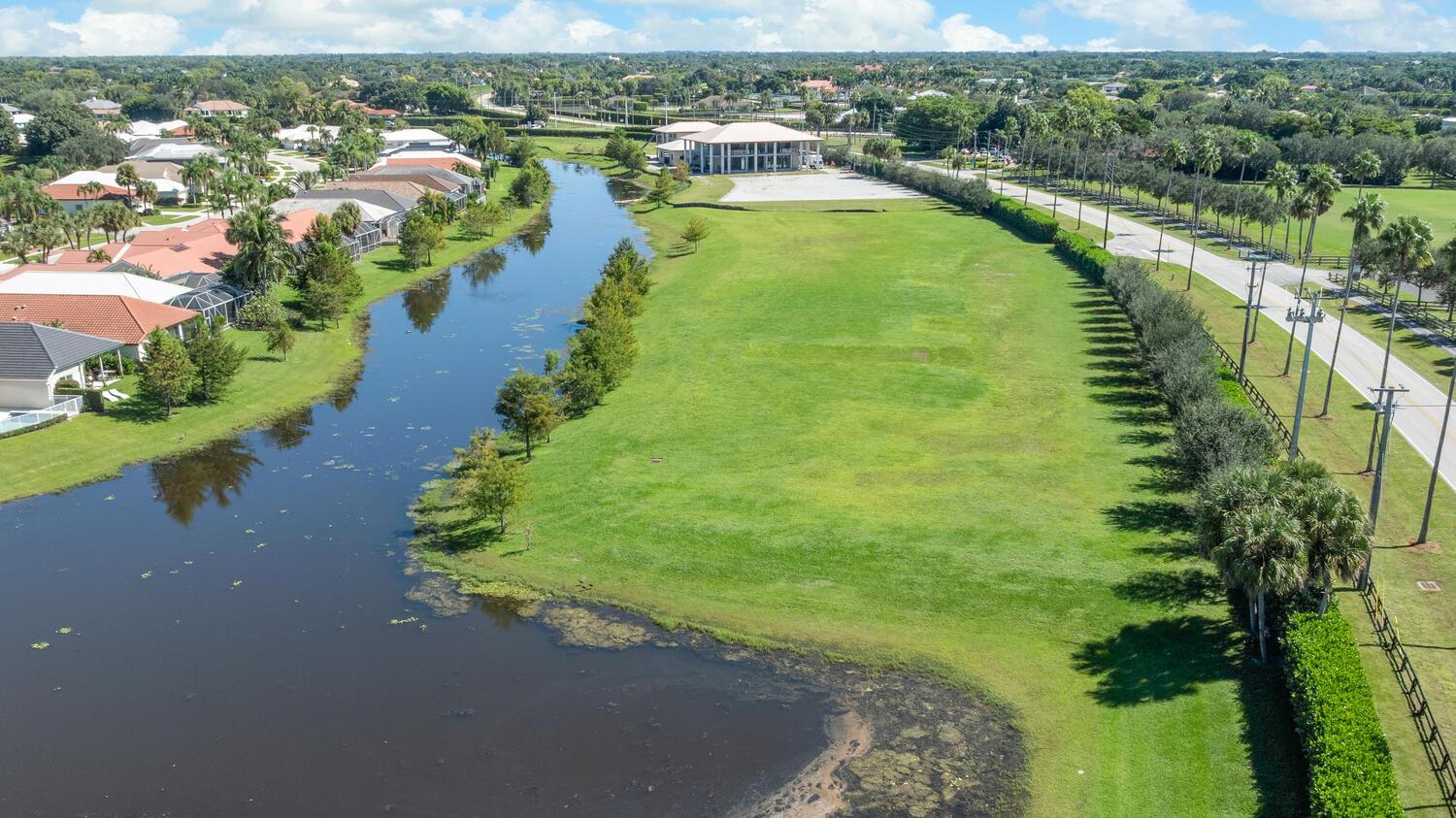 An aerial view shows a large grassy lot beside a canal and a residential neighborhood — 2970 Greenbriar Boulevard, Wellington FL 33414, WELLINGTON, FL