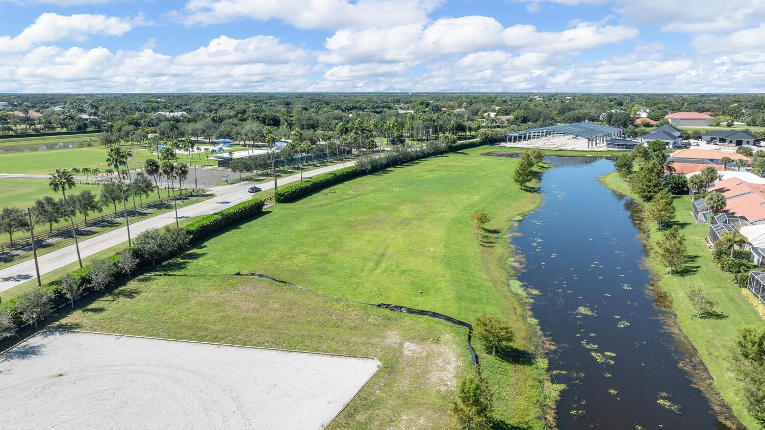 An aerial view shows a grassy lot next to a canal, a road, and nearby houses — 2970 Greenbriar Boulevard, Wellington FL 33414, WELLINGTON, FL