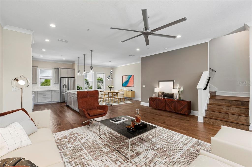 An open-concept living room and kitchen featuring hardwood floors, a ceiling fan, and stairs — 2442 W MISSISSIPPI AVENUE UNIT 14, TAMPA, FL