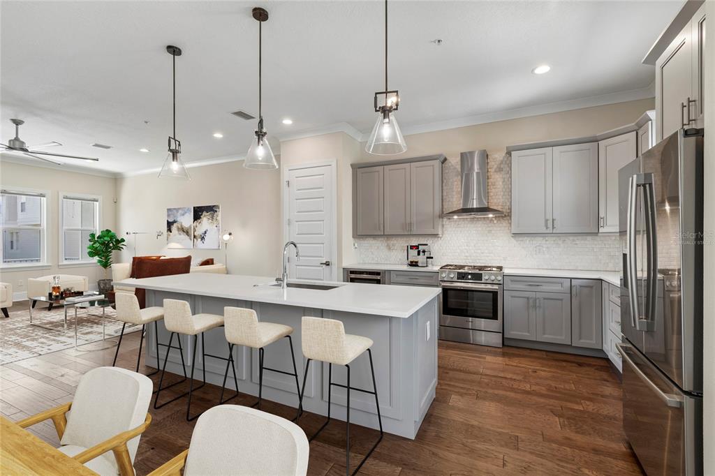 A modern kitchen features gray cabinets, a white island with bar seating, and hardwood floors — 2442 W MISSISSIPPI AVENUE UNIT 14, TAMPA, FL
