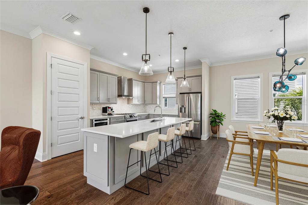 A modern kitchen features gray cabinetry, a white quartz island with bar seating, and hardwood floors — 2442 W MISSISSIPPI AVENUE UNIT 14, TAMPA, FL