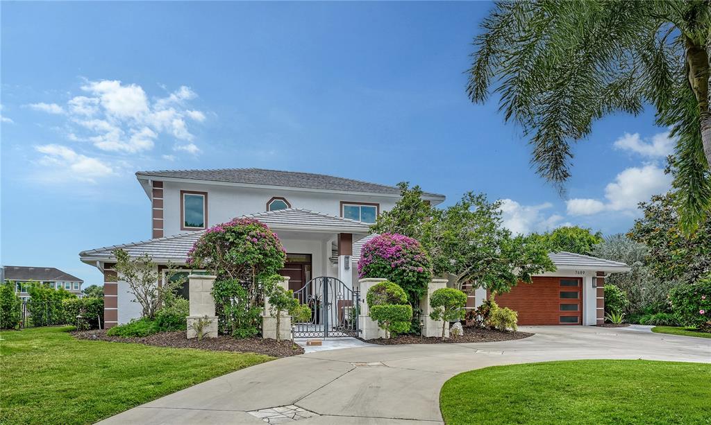 A two-story house with a white exterior, a gated courtyard, and an attached garage — 7689 COVE TERRACE, SARASOTA, FL