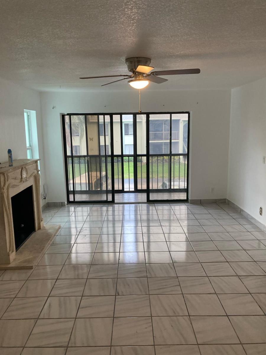 A living room with white tile floors, a fireplace, and a sliding glass door — WEST PALM BEACH, FL