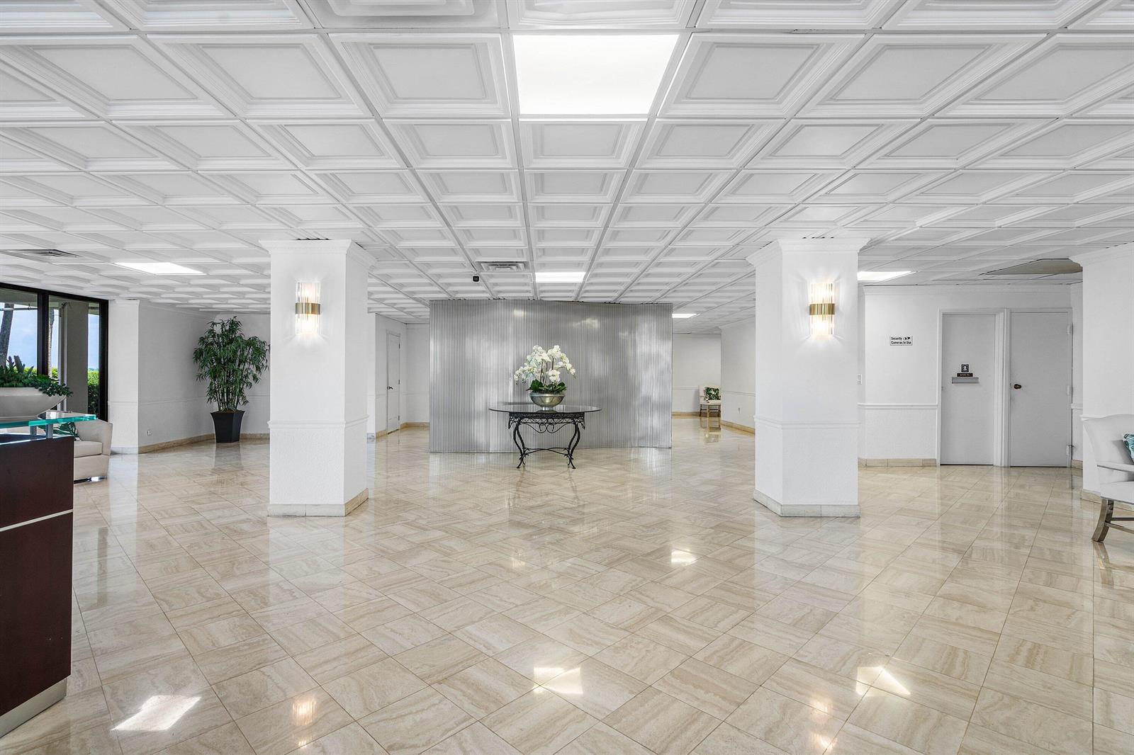 A bright lobby features a coffered ceiling, marble tile floors, and two prominent white columns — 3460 S Ocean Boulevard # 1080, Palm Beach FL 33480, PALM BEACH, FL