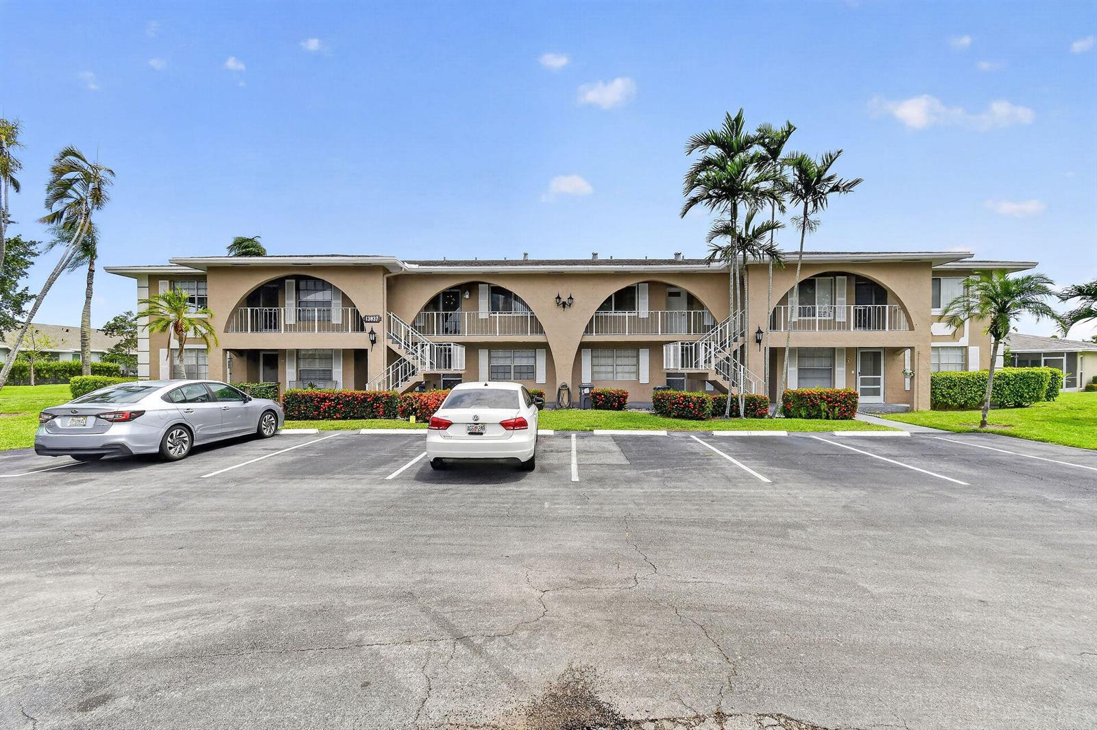 A two-story apartment building with arched balconies and a parking lot in front — 13837 Via Flora, Delray Beach FL 33484, DELRAY BEACH, FL