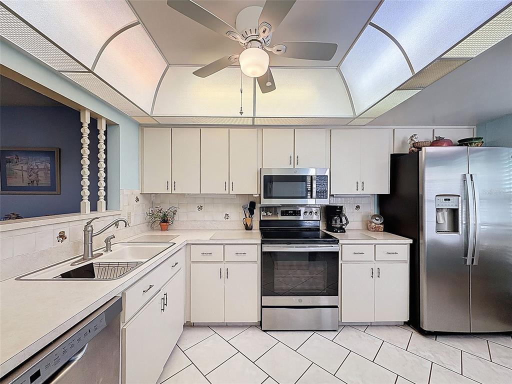A kitchen features white cabinets, stainless steel appliances, a tile floor, and a tray ceiling — 11241 VERSAILLES LANE UNIT 0, PORT RICHEY, FL