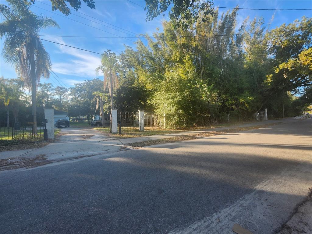 A paved driveway leads to a gated entrance surrounded by trees and residential landscaping — 7224 N OLA AVENUE, TAMPA, FL