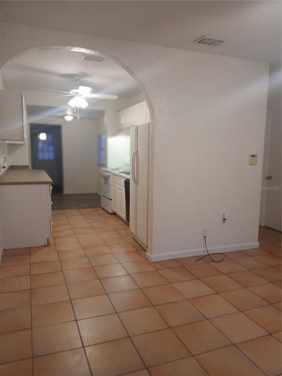 A kitchen with white cabinets and appliances is viewed through an arched doorway from a room — 5410 70TH WAY N, ST PETERSBURG, FL